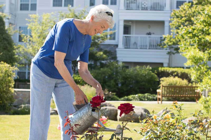 a815264c-community_life_testimonial2 senior woman waters flowers in her garden