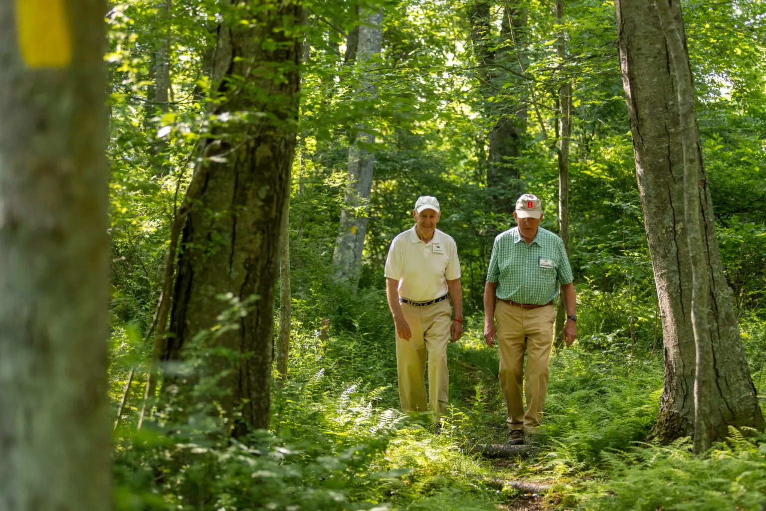 Two senior men walking through wooded path at StoneRidge a senior living community in Mystic, Connecticut.