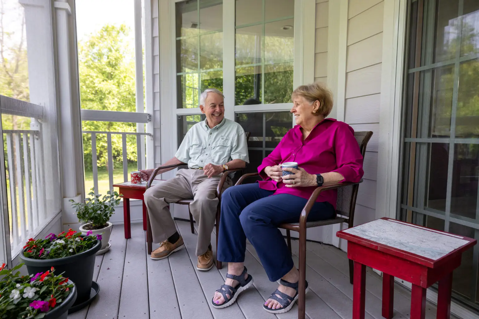 Senior man and woman sitting on porch discussing the growth at StoneRidge in Mystic, CT.