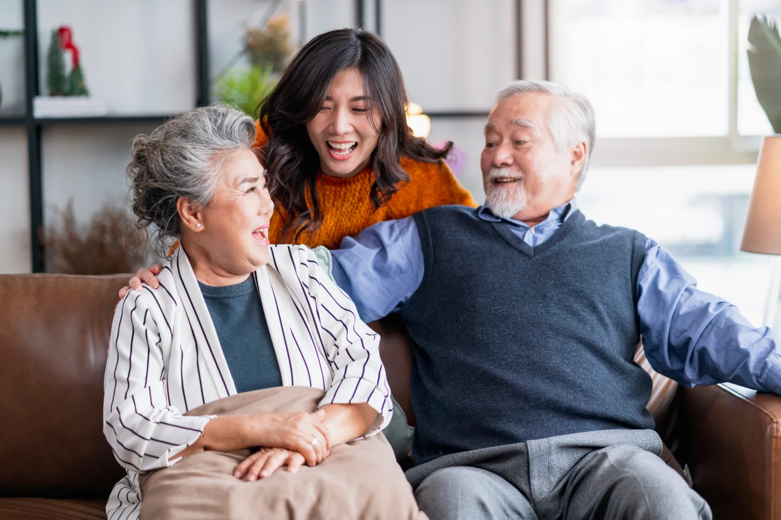 An adult woman hugging her elderly parents and wanting to help her aging parents by discussing independent living options in Mystic, CT like StoneRidge.
