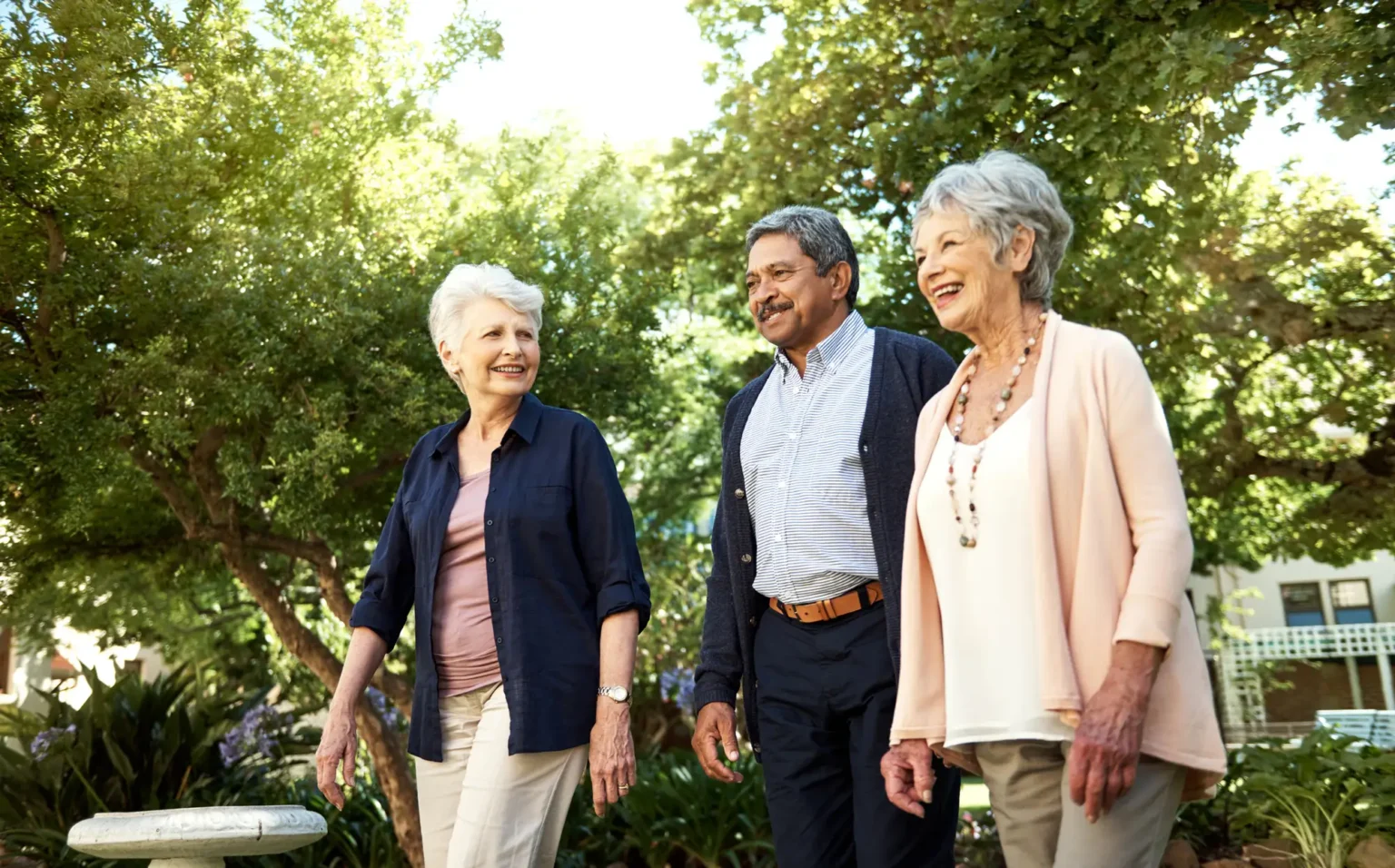 Three elderly adults touring outside of StoneRidge while discussing how to choose a senior living community in CT.