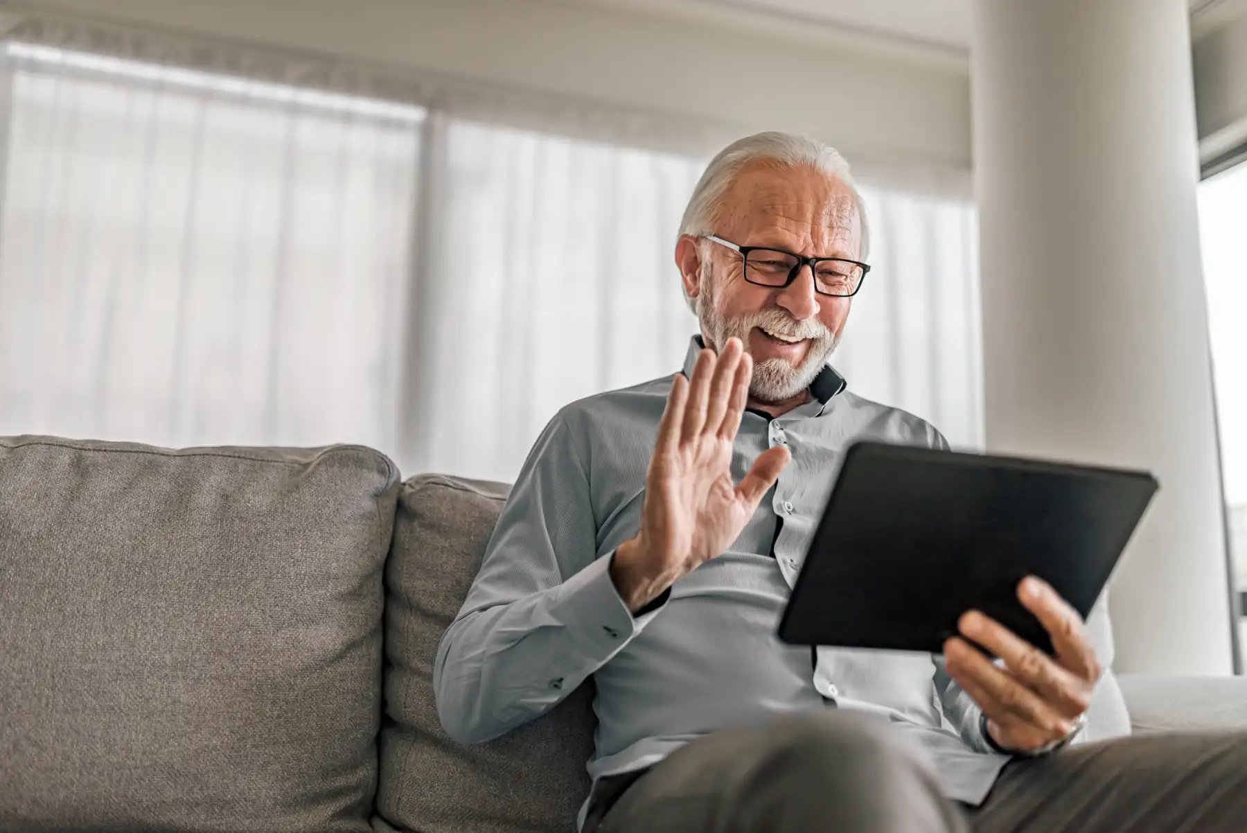 a senior man video chatting with family on his tablet